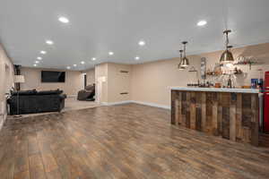 Bar with pendant lighting, dark wood-type flooring, and sink