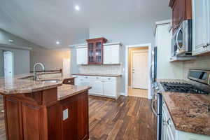 Kitchen with white cabinets, decorative backsplash, stainless steel appliances, and an island with sink