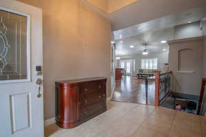 Entryway with ceiling fan with notable chandelier and light tile patterned flooring