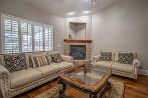 Living room with ceiling fan, a fireplace, lofted ceiling, and hardwood / wood-style flooring