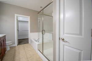 Full bathroom featuring plus walk in shower, vanity, tile patterned floors, and toilet