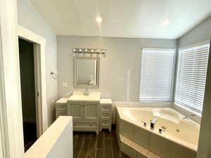 Bathroom with vanity, a relaxing tiled tub, and a textured ceiling