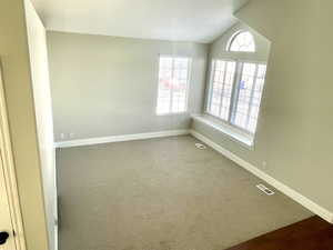 Carpeted empty room with vaulted ceiling