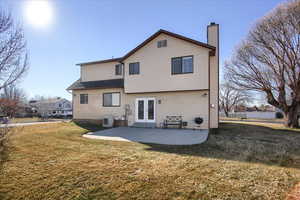 Back of property with a patio area, a yard, french doors, and central AC