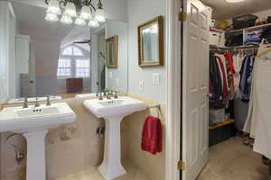 Bathroom with tile patterned flooring, a textured ceiling, vaulted ceiling, and ceiling fan