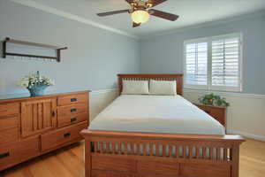 Bedroom with light hardwood / wood-style floors, ceiling fan, and crown molding