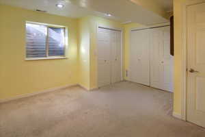 Unfurnished bedroom with light colored carpet and multiple closets