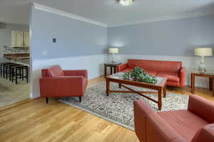 Living room with light hardwood / wood-style flooring and crown molding