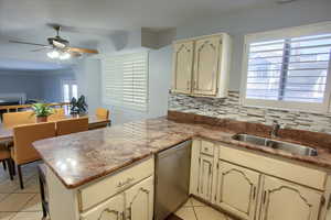 Kitchen featuring dishwasher, cream cabinets, tasteful backsplash, and light tile patterned flooring