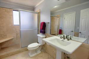 Bathroom with toilet, tile patterned floors, a shower with shower door, and ornamental molding