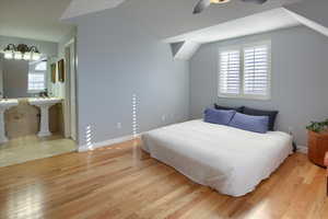 Bedroom with ceiling fan, light wood-type flooring, and vaulted ceiling