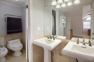 Bathroom with sink, tile patterned flooring, a bidet, toilet, and ornamental molding