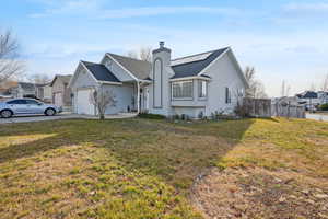 Ranch-style house featuring solar panels, a front yard, and a garage