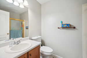 Bathroom featuring vanity, toilet, and a shower with shower door