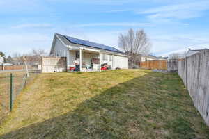 Back of house featuring solar panels and a yard