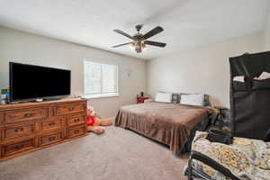 Carpeted bedroom featuring ceiling fan and a textured ceiling