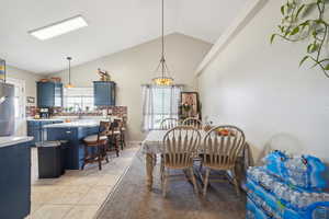 Dining area with light tile patterned floors, sink, and vaulted ceiling