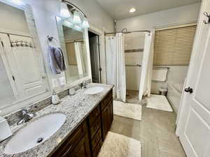 Bathroom featuring shower / tub combo with curtain, vanity, and tile patterned flooring