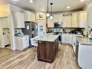 Kitchen with decorative backsplash, sink, hanging light fixtures, and appliances with stainless steel finishes