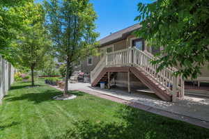 Back of house with a lawn, a patio, and a deck