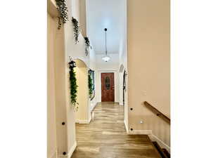 Hall with a high ceiling and light wood-type flooring