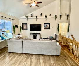 Living room with ceiling fan, wood-type flooring, a textured ceiling, and vaulted ceiling