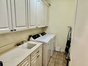 Main Floor Laundry area featuring cabinets, independent washer and dryer, sink, and light tile patterned floors