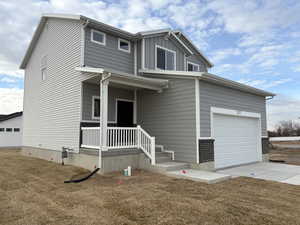 View of front facade with a front lawn, covered porch, and a garage