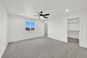 Unfurnished bedroom featuring carpet flooring, ceiling fan, and a spacious closet