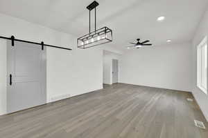 Interior space featuring light hardwood / wood-style flooring, a barn door, and ceiling fan