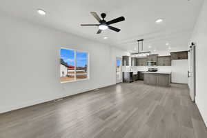 Unfurnished living room with sink, light hardwood / wood-style flooring, a barn door, and ceiling fan