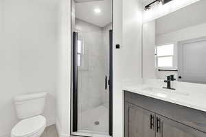 Bathroom featuring vanity, toilet, and an enclosed shower