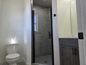 Bathroom with tile patterned flooring, vanity, toilet, and a shower with door