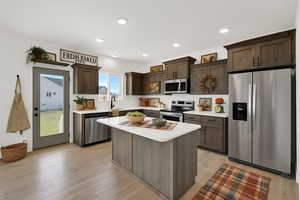 Kitchen featuring stainless steel appliances, dark brown cabinets, a sink, light countertops, and recessed lighting