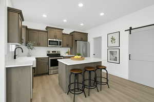 Kitchen with appliances with stainless steel finishes, decorative backsplash, a breakfast bar, and light wood finished floors