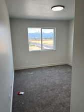 Empty room featuring dark carpet and a textured ceiling