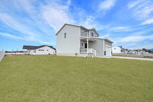 Rear view of house featuring a porch and a lawn