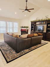 Living room with hardwood / wood-style floors, ceiling fan, lofted ceiling, and a premium fireplace