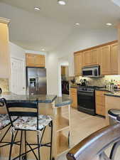 Kitchen featuring lofted ceiling, a kitchen breakfast bar, appliances with stainless steel finishes, kitchen peninsula, and washing machine and clothes dryer