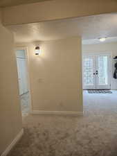 Carpeted spare room featuring french doors and a textured ceiling