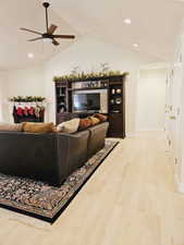 Living room with ceiling fan, light hardwood / wood-style floors, and vaulted ceiling