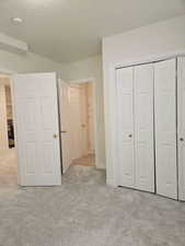 Unfurnished bedroom with light carpet, a closet, and a textured ceiling