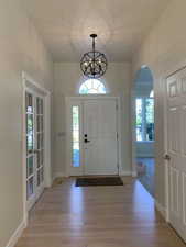 Entryway with french doors, plenty of natural light, a notable chandelier, and light wood-type flooring