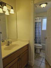 Full bathroom with toilet, shower / bath combination with curtain, vanity, and tile patterned floors