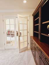 Doorway featuring french doors, light colored carpet, and ornamental molding