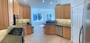 Kitchen featuring sink, hanging light fixtures, stainless steel appliances, light hardwood / wood-style floors, and a chandelier