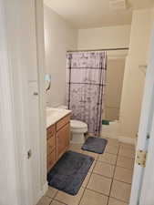 Full bathroom featuring shower / bathtub combination with curtain, tile patterned flooring, vanity, and toilet