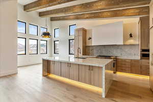 Kitchen with sink, decorative light fixtures, decorative backsplash, custom range hood, and appliances with stainless steel finishes