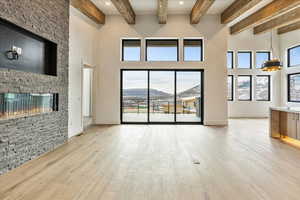 Unfurnished living room featuring beam ceiling, a mountain view, a fireplace, and light hardwood / wood-style flooring