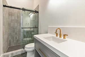 Bathroom with tile patterned flooring, vanity, toilet, and a shower with door